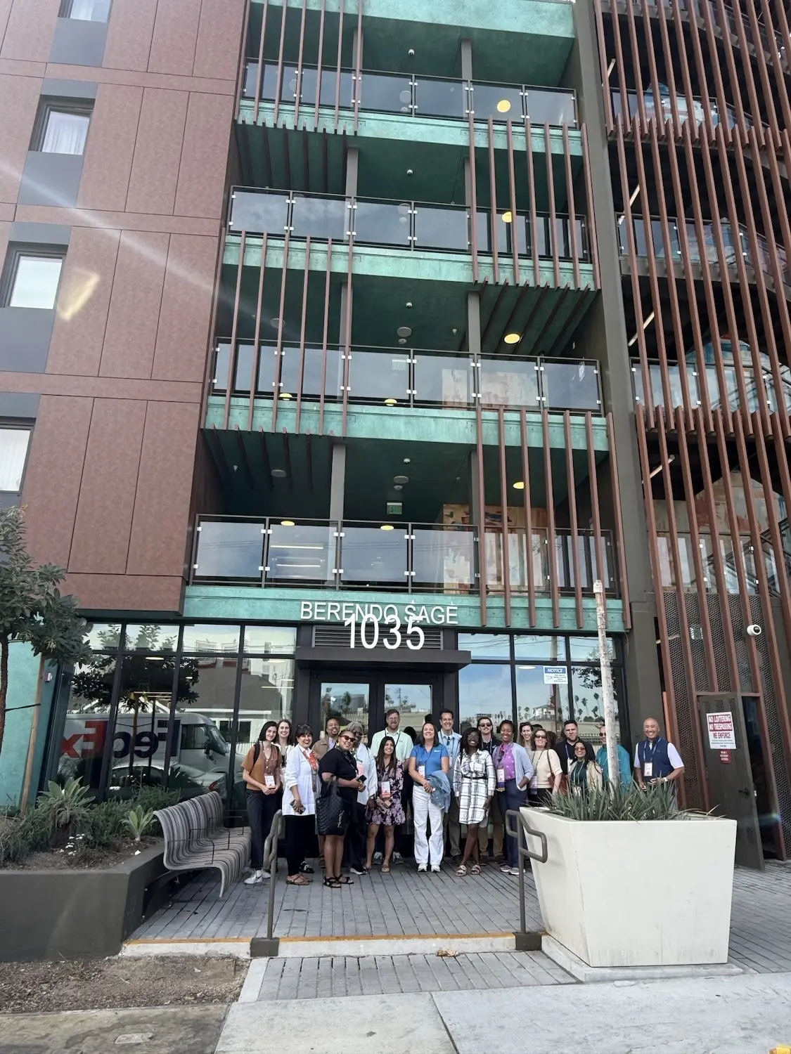 A group of people gathered in front of a modern, stylish apartment building.