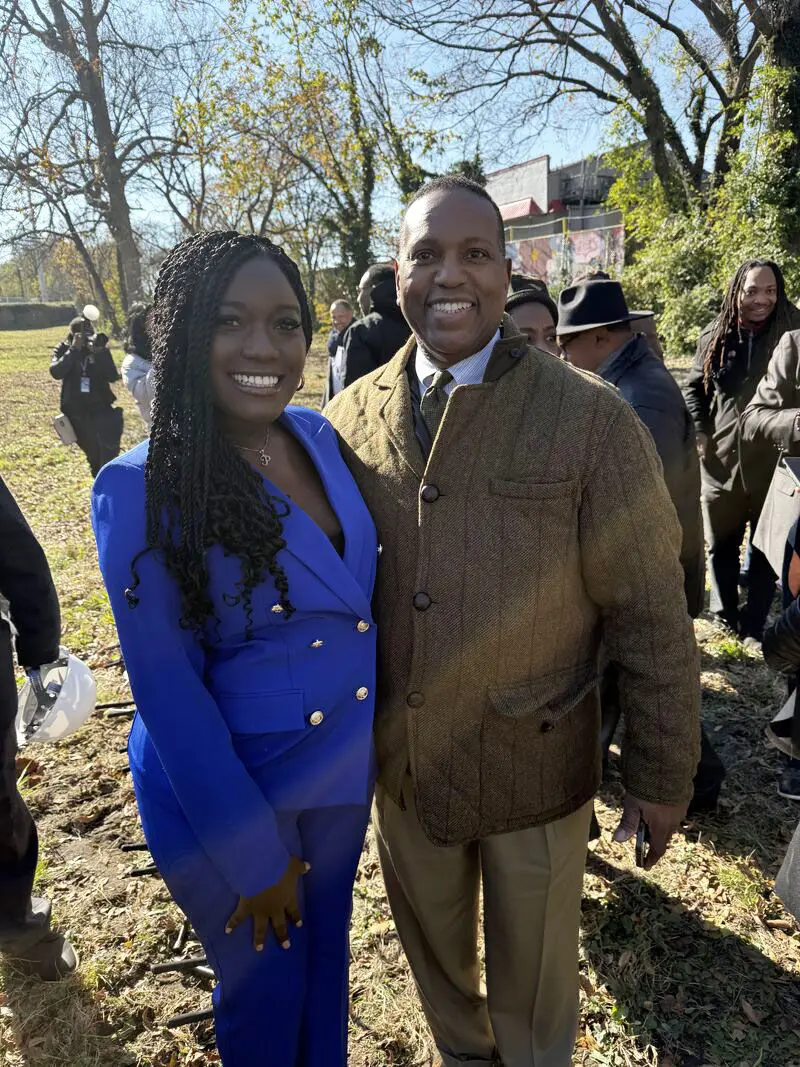 A woman and a man pose together for a photo outside on a sunny day.