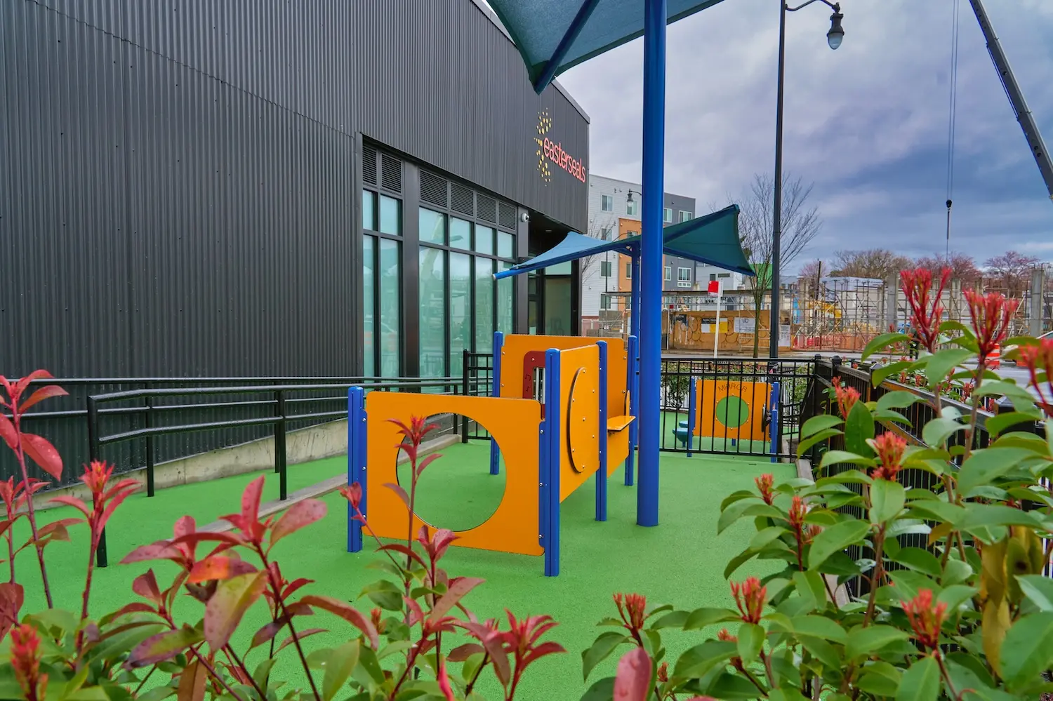 A playground filled with bright play equipment, situated in front of a building.