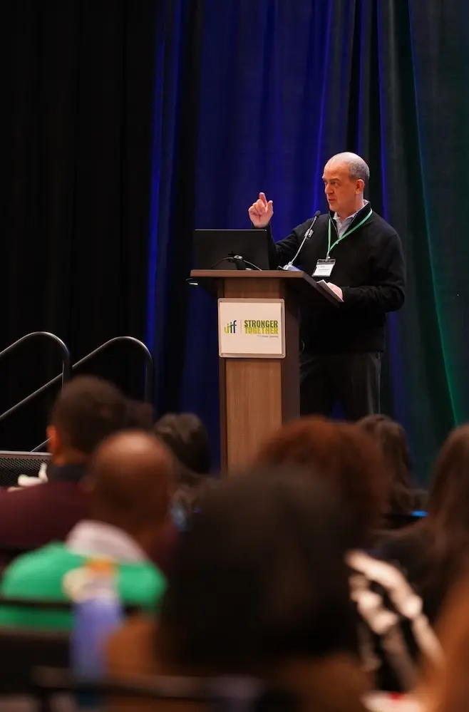 A man standing at a podium delivering a presentation to an audience.