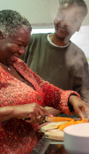 Man and woman smiling as the woman cuts vegetables