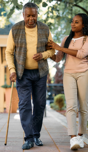 Young woman helping elderly man walk down the street